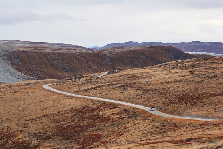 Photo from above of a car driving on a road through the nature near Kangerlussuaq